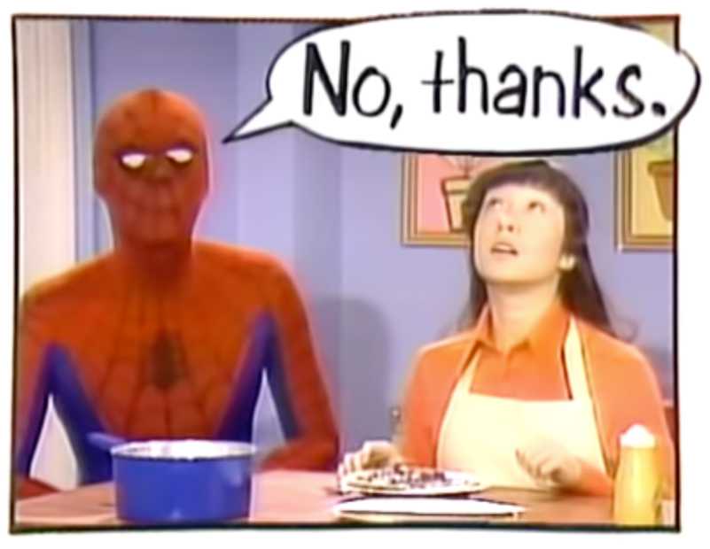 A shot from the Spider-Man segment of the Electric Company TV show. Spider-Man and a woman are in what looks like a kitchen. The woman is wearing an apron. The two are behind a tall table that has a pot and some plates with food on it. A large text bubble shows Spider-Man is saying “No, thanks.” A shot from the Spider-Man segment of the Electric Company TV show. Spider-Man and a woman are in what looks like a kitchen. The woman is wearing an apron. The two are behind a tall table that has a pot and some plates with food on it. A large text bubble shows Spider-Man is saying “No, thanks.”